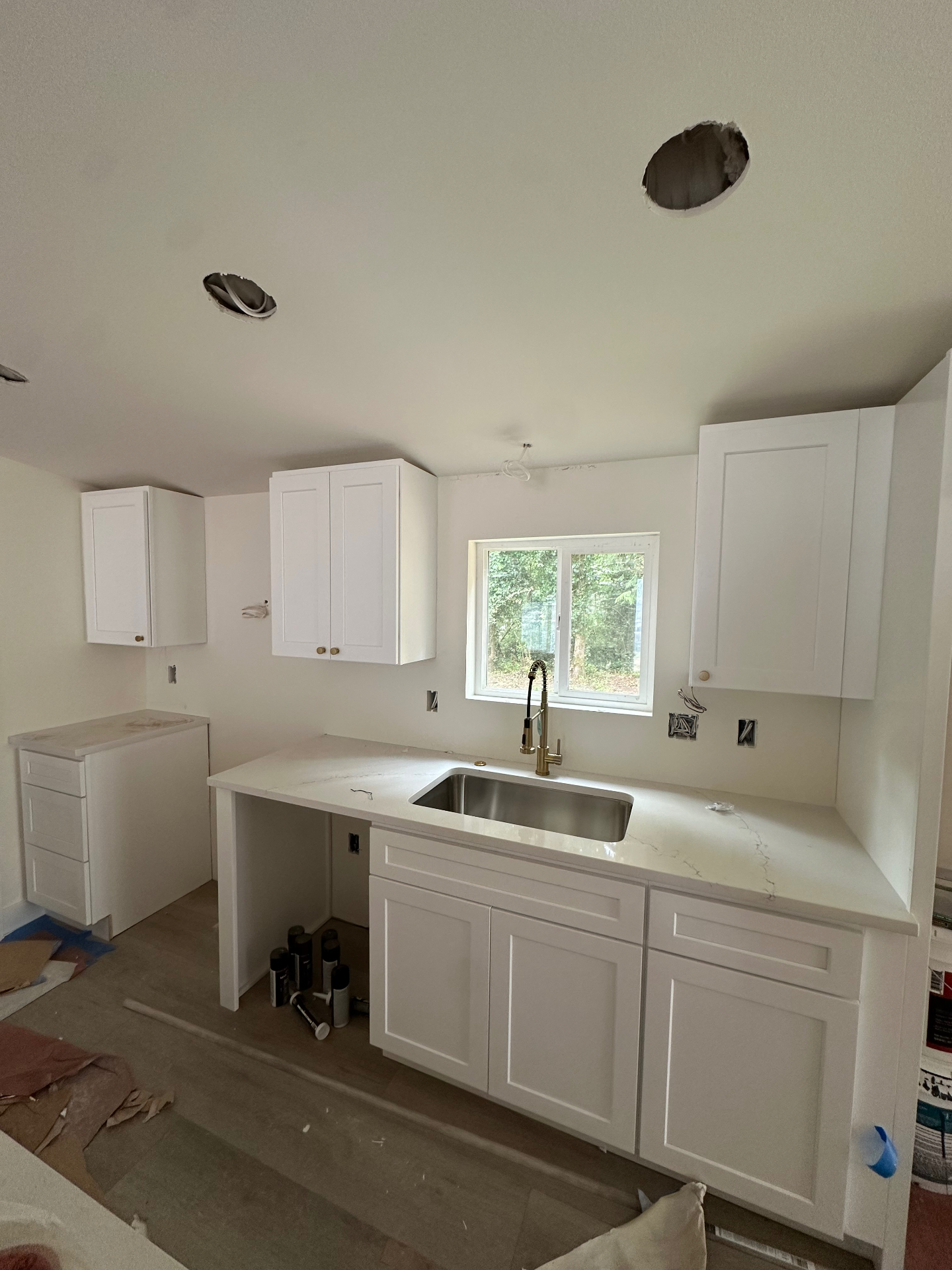 Before: Seattle kitchen with white shaker cabinets, quartz countertop, and blank painted drywall wall behind the sink — waiting for the 24x48 tile backsplash install