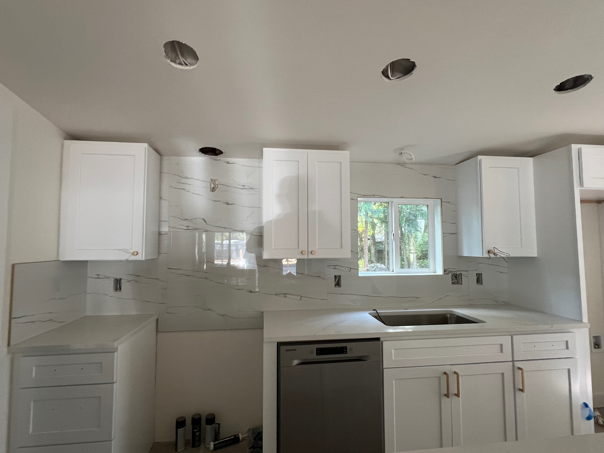 24x48 marble-look porcelain slab backsplash installed floor-to-ceiling in a Seattle kitchen with white shaker cabinets and quartz countertops — NorthWest Home Remodeling install