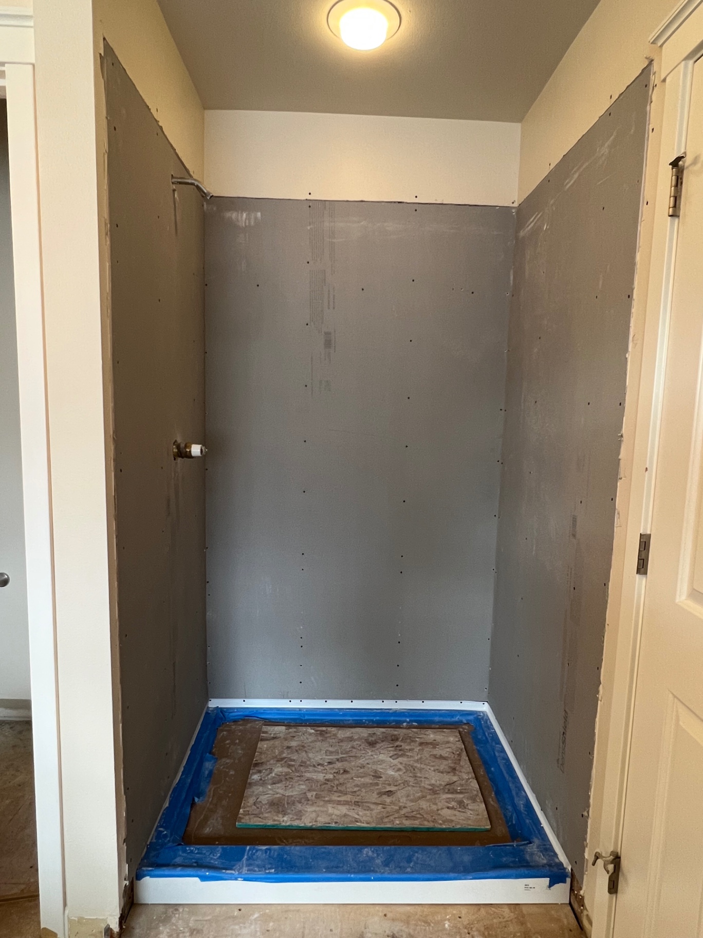 Before: tub alcove with new gray cement backer board, taped shower pan flanges and waterproofing prep — ready for tile in a Kent hall bathroom.