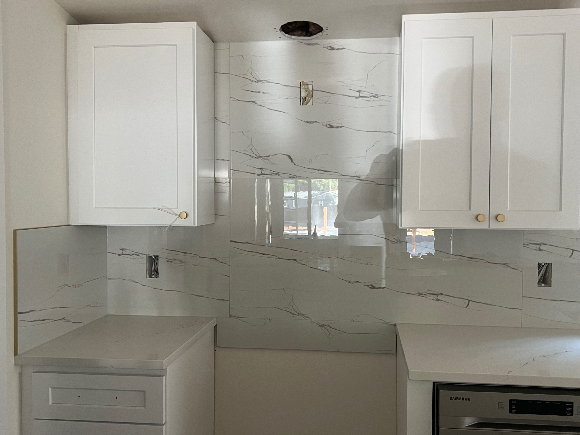 Close-up of a 24x48 marble-look porcelain slab backsplash with continuous horizontal veining behind a Seattle kitchen range wall